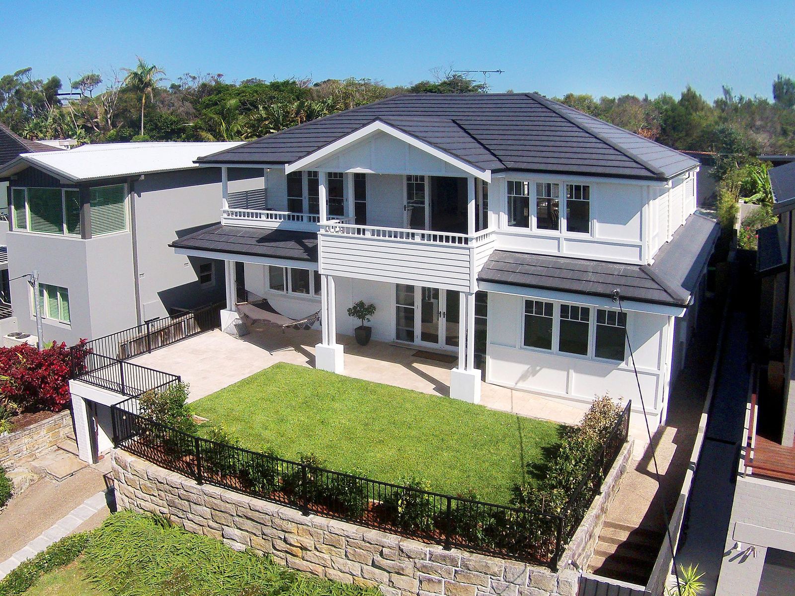 Balgowlah Heights, elevated view of a Hamptons-style two-storey home with lawn and sandstone wall, built by HP Constructions with All Australian Architecture