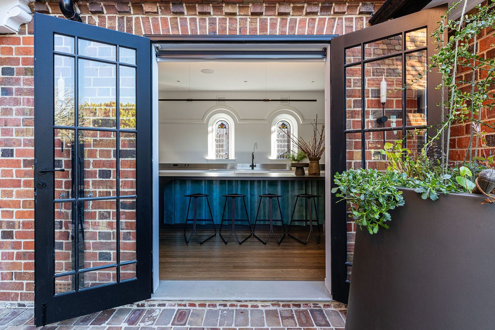 Bellevue Hill, black steel-framed glass doors in a red-brick wall opening onto a kitchen, built by HP Constructions with Foster & Associates