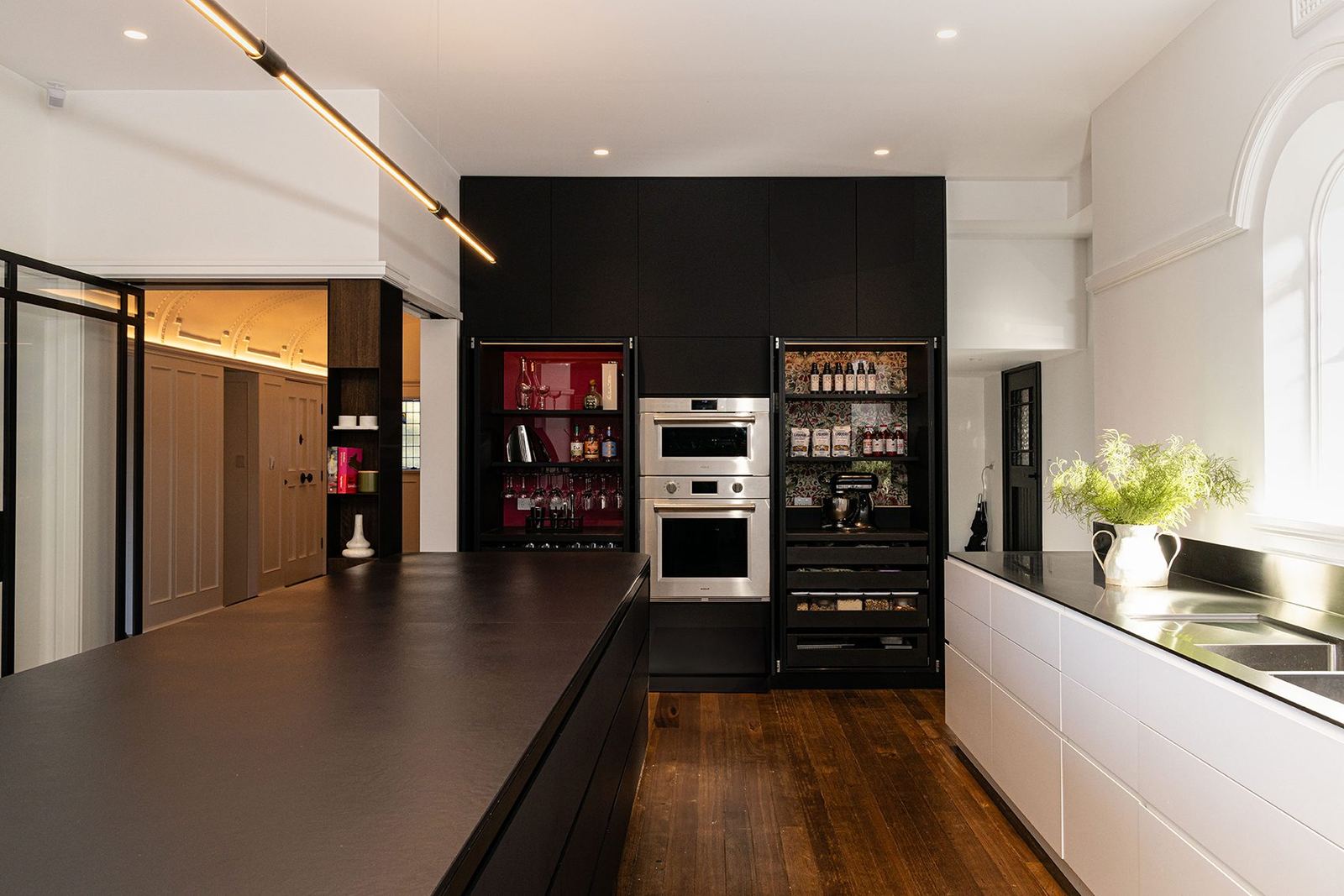 Bellevue Hill, long dark stone kitchen island with black cabinetry, wall ovens and timber floor, built by HP Constructions with Foster & Associates