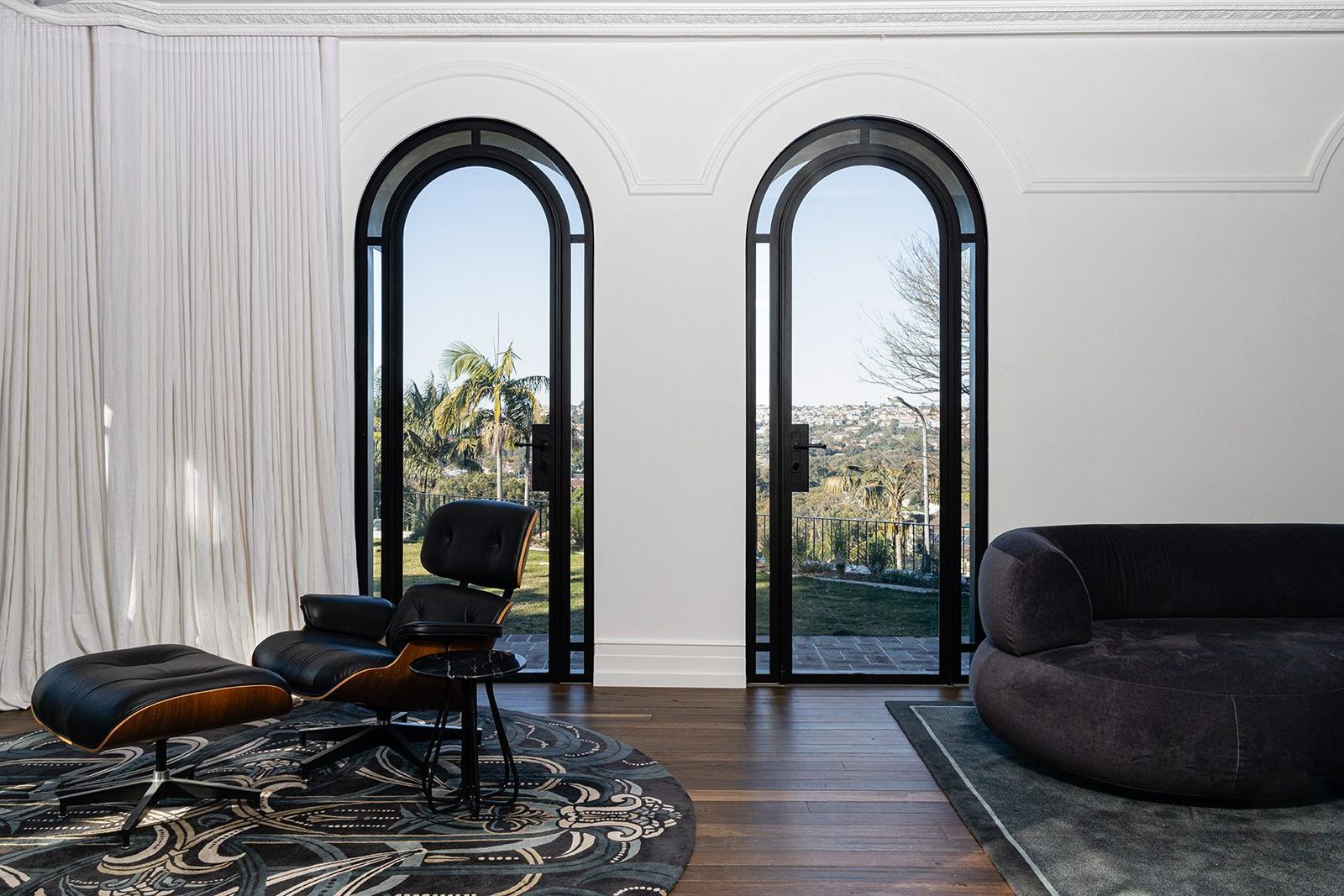 Bellevue Hill, living room with twin arched steel doors, Eames lounge chair and patterned rug, built by HP Constructions with Foster & Associates