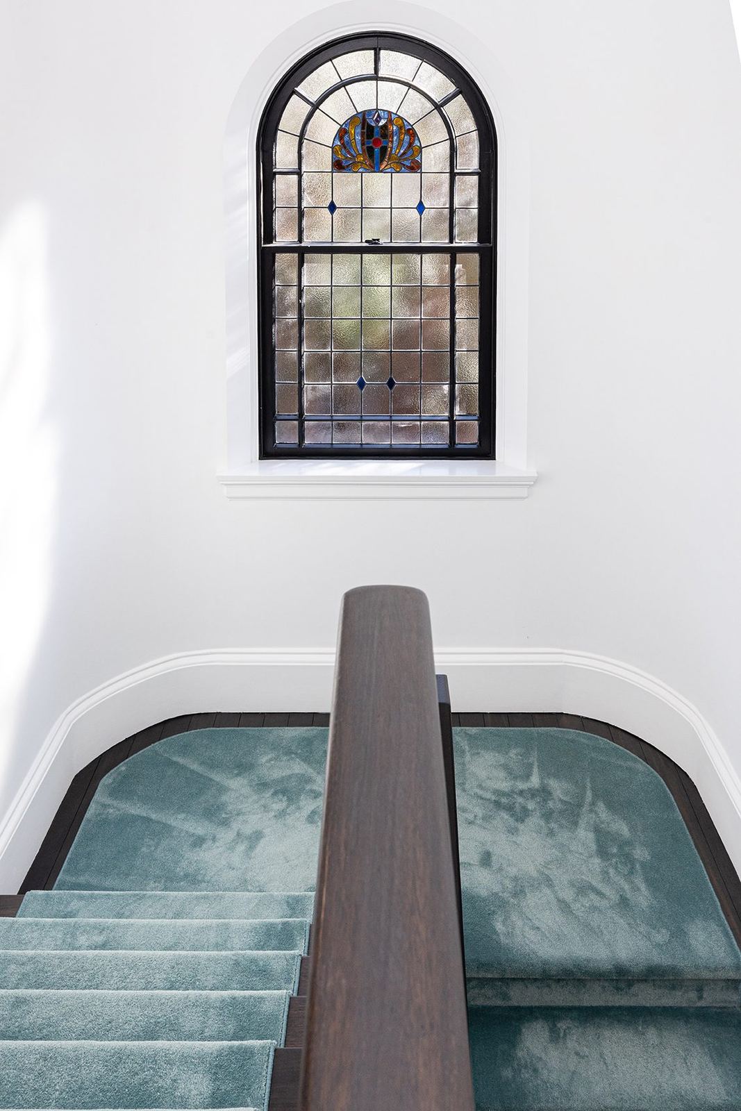 Bellevue Hill, curved staircase with teal carpet beneath an arched stained-glass window, built by HP Constructions with Foster & Associates