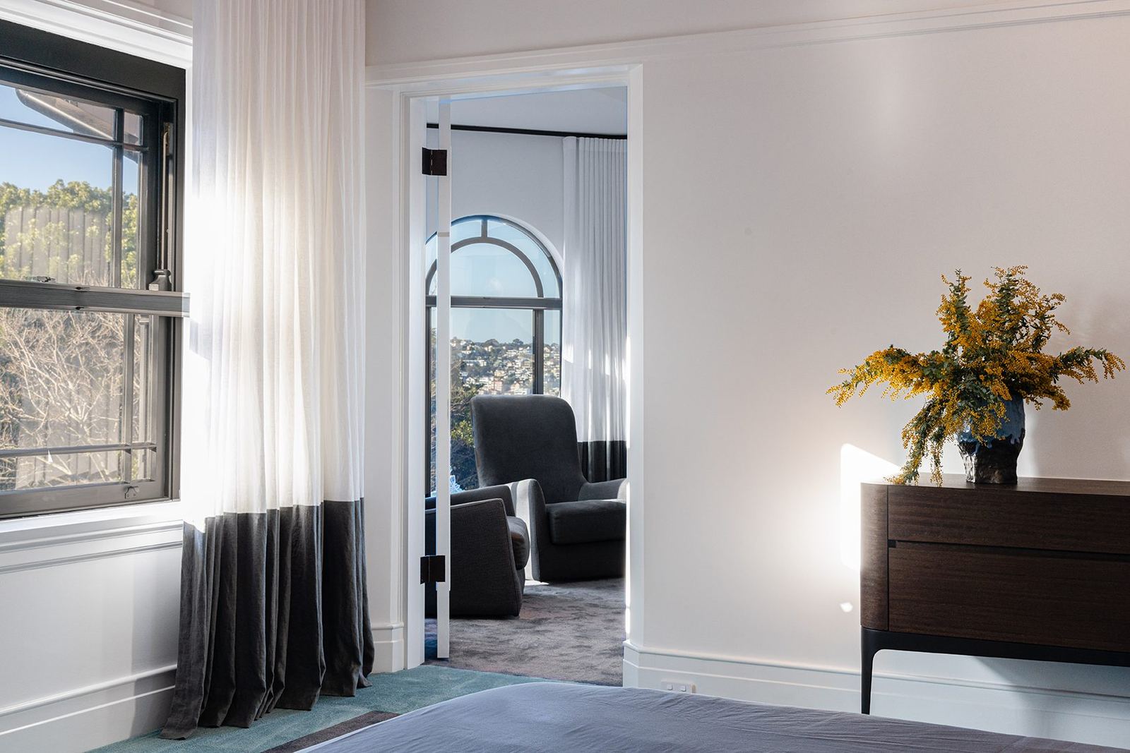 Bellevue Hill, carpeted bedroom with arched window, sheer curtains and dark timber sideboard, built by HP Constructions with Foster & Associates