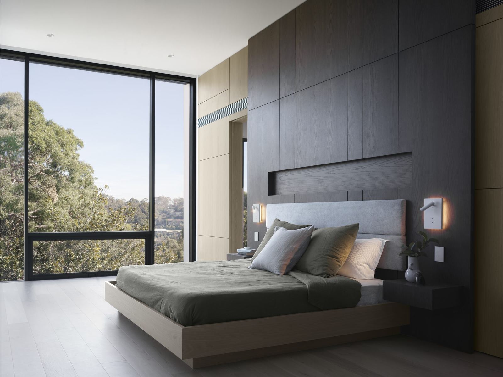 Castle Cove, bedroom with dark timber wall, green bedding and corner glazing to trees, built by HP Constructions with Dieppe Design