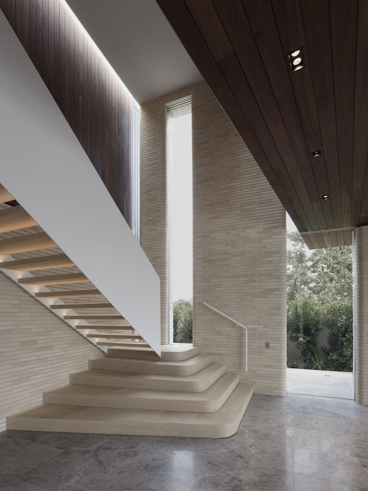 Castlecrag, sculptural travertine staircase beneath timber-lined ceiling with garden glazing, built by HP Constructions with FJC Studio