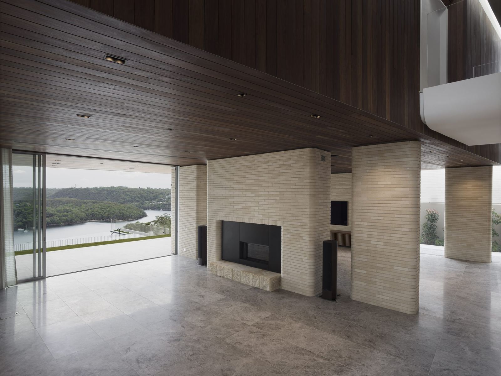 Castlecrag, living room with timber-lined ceiling, stone floor and fireplace facing bushland glazing, built by HP Constructions with FJC Studio