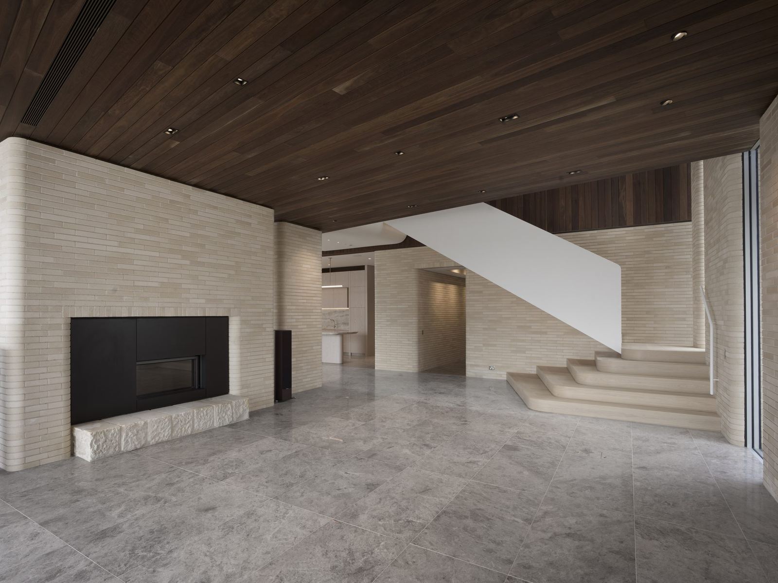 Castlecrag, living area with fireplace, curved travertine stair and stone floor, built by HP Constructions with FJC Studio