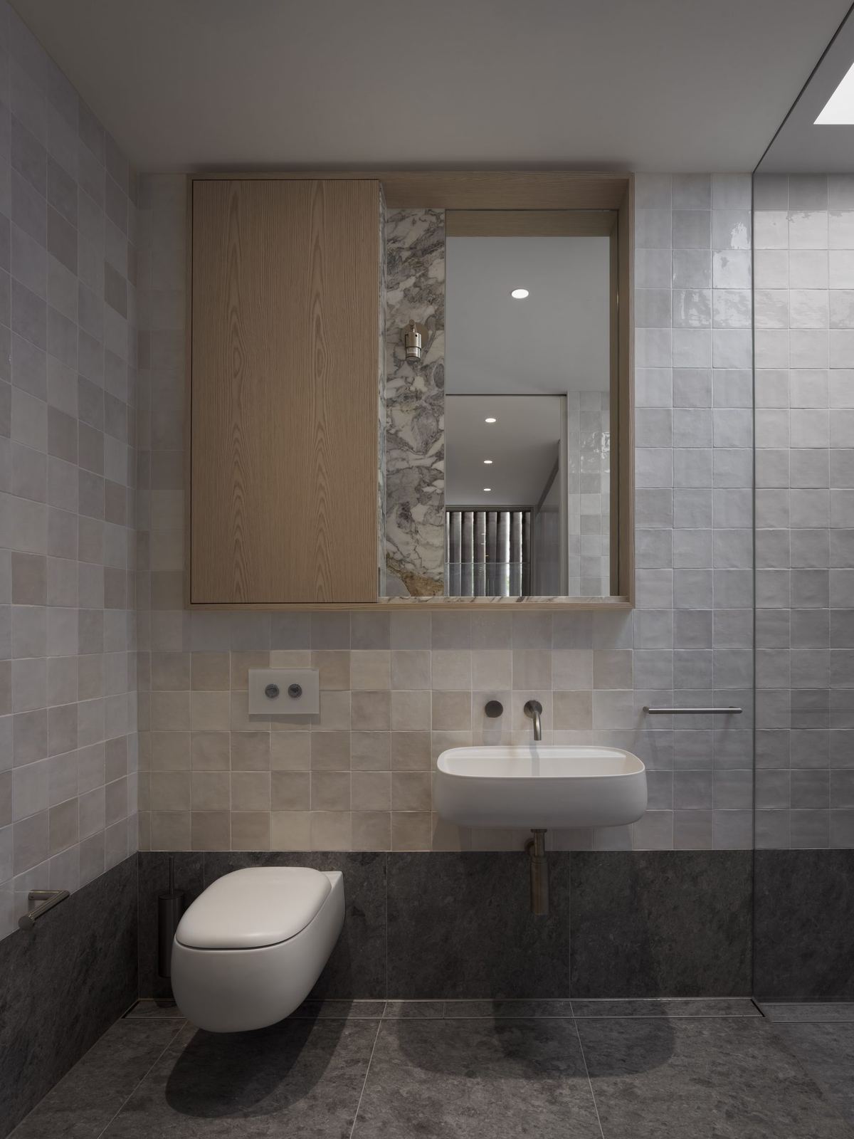 Castlecrag, bathroom with stone-tiled walls, wall-hung toilet and timber-framed mirror, built by HP Constructions with FJC Studio