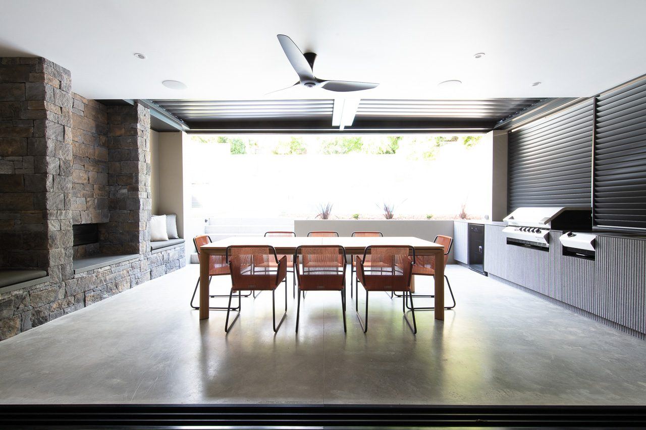 Hunters Hill, covered outdoor room with stacked-stone fireplace, dining table and built-in barbecue, built by HP Constructions with Dale Design Group