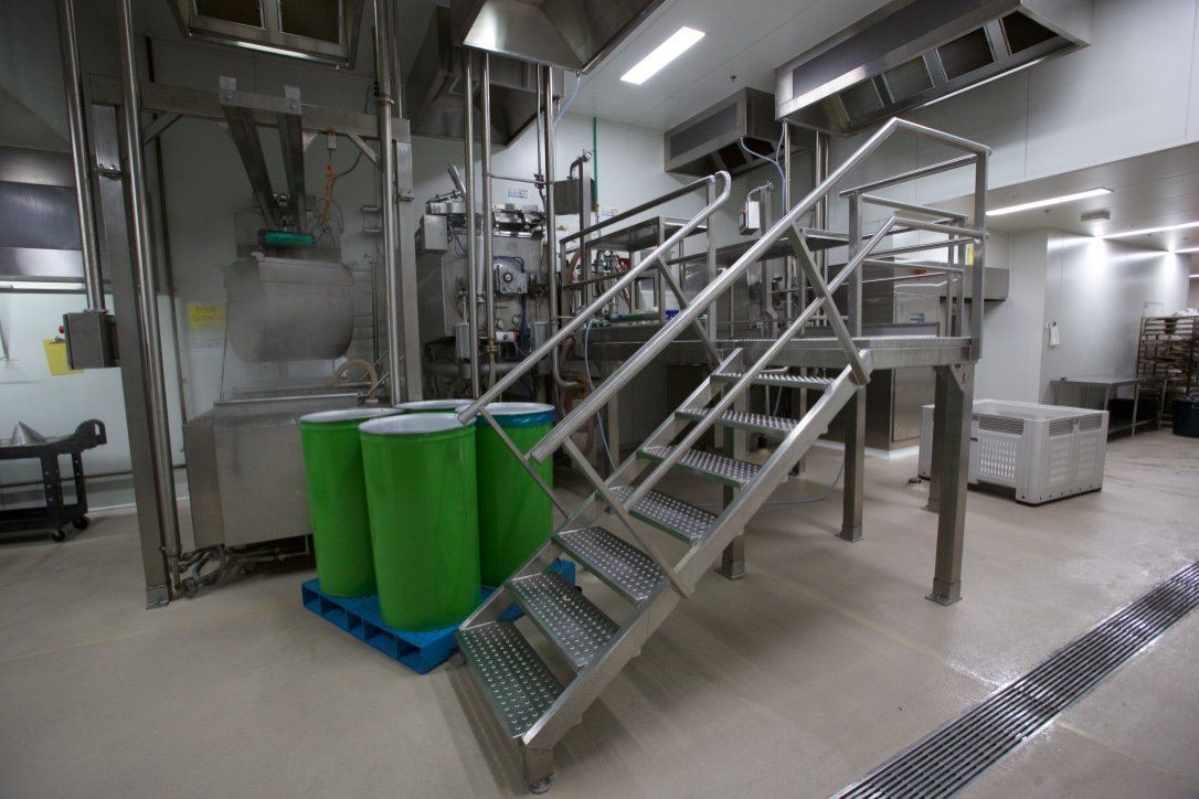 Kitchen Food Company, stainless processing area with elevated platform stairs and green bins, built by HP Constructions