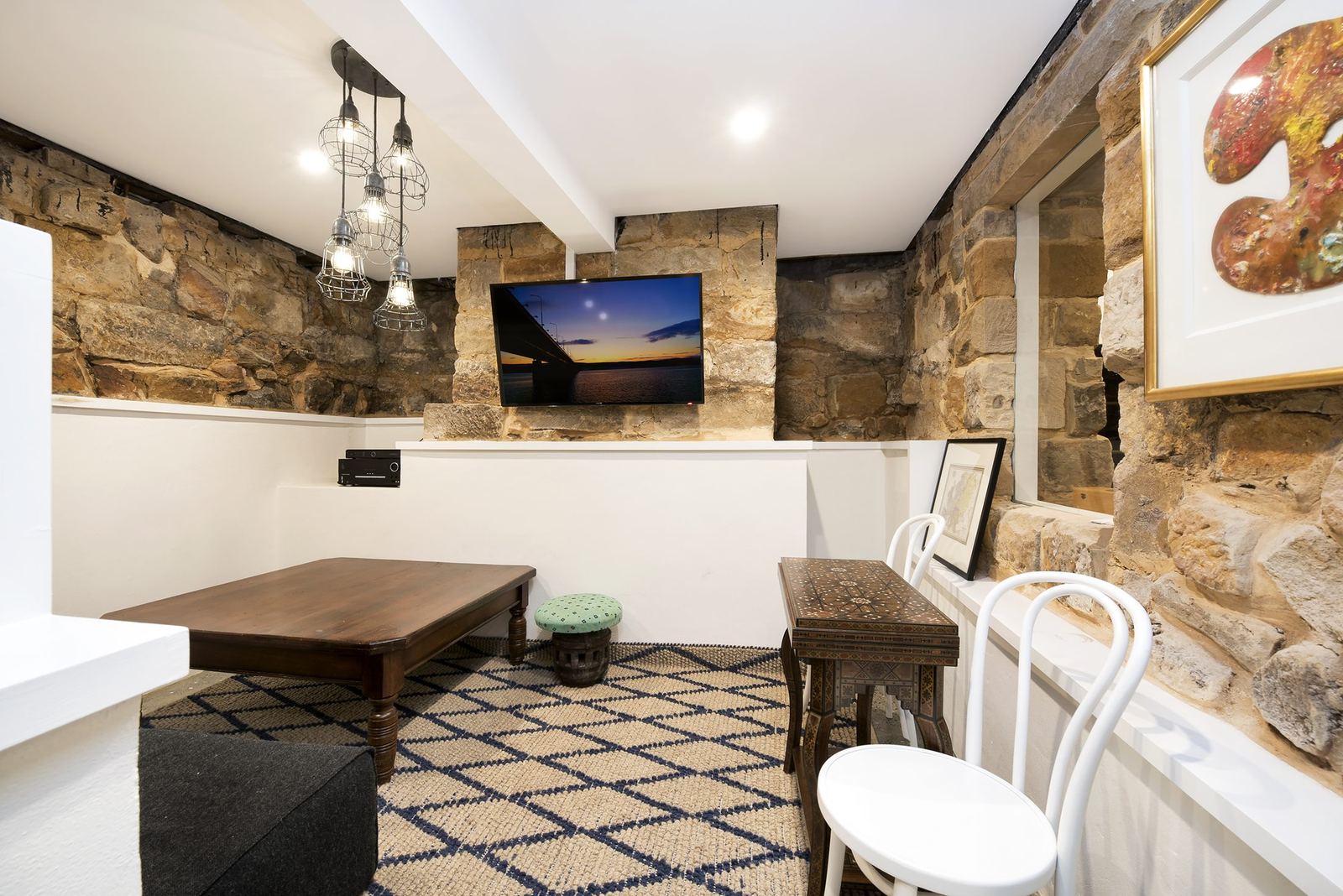 Paddington, living room with exposed sandstone walls, mounted television and patterned rug, built by HP Constructions with Gutnik Design Group