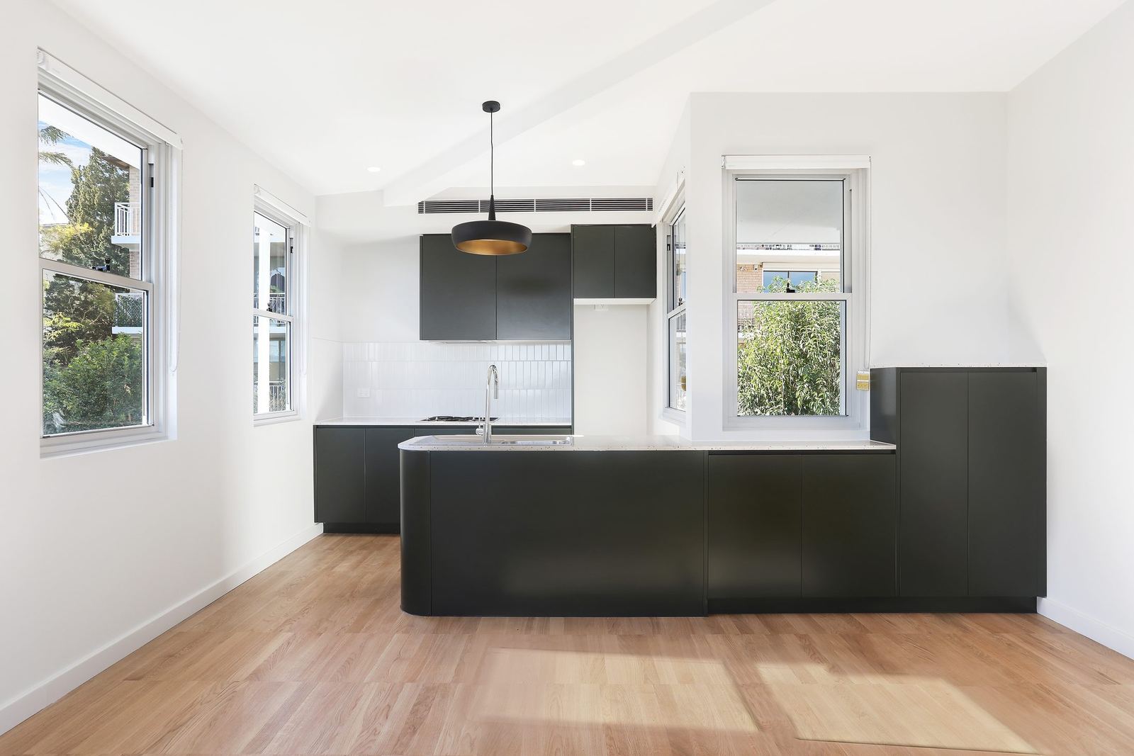 Queens Park Apartments, empty apartment kitchen with black island and timber floor, built by HP Constructions with Ignite Architects