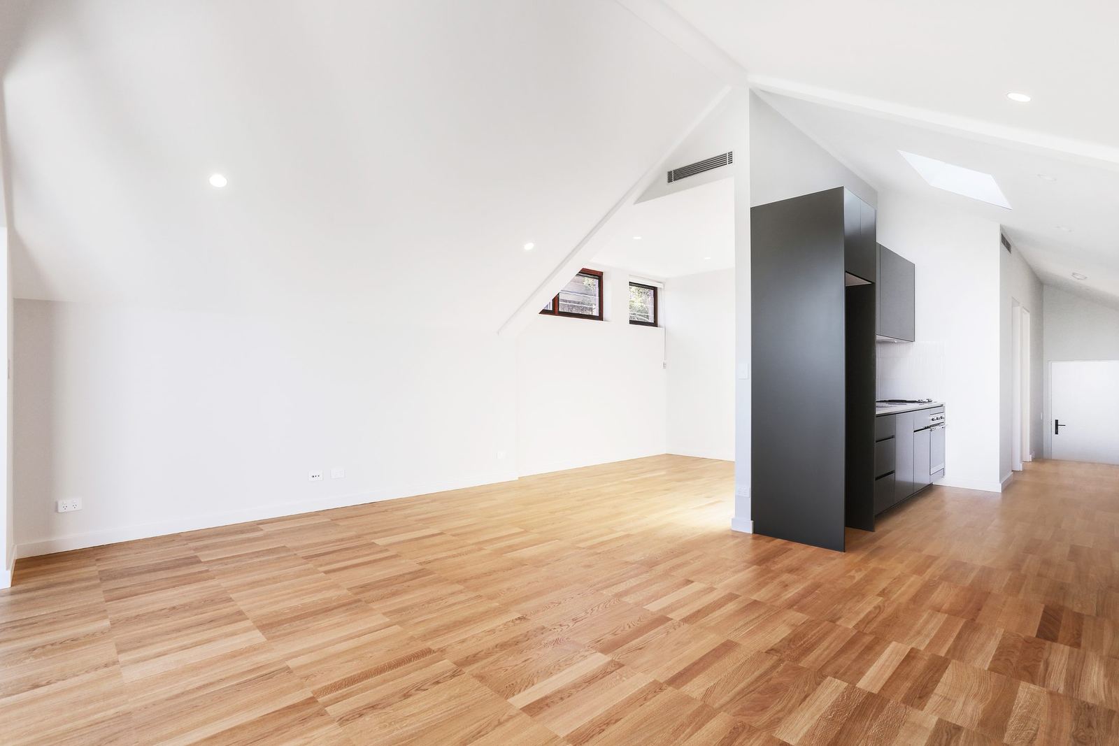 Queens Park Apartments, empty loft room with angled ceiling and black joinery, built by HP Constructions with Ignite Architects