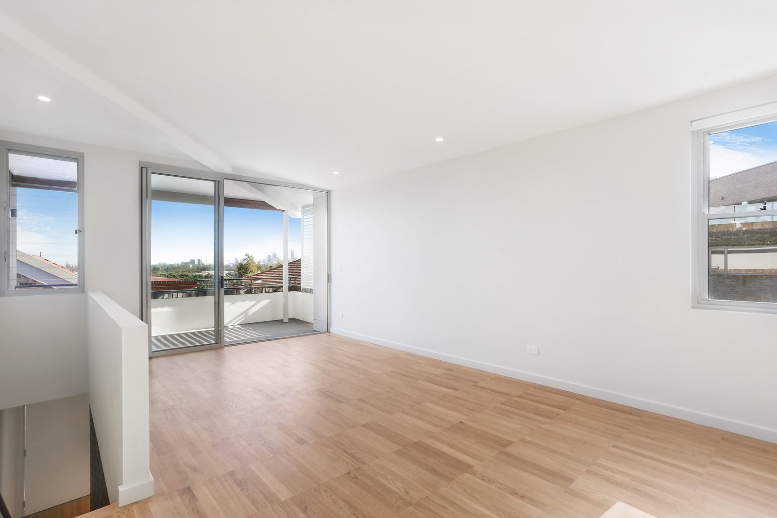 Queens Park Apartments, vacant living room with sliding balcony door and timber floor, built by HP Constructions with Ignite Architects