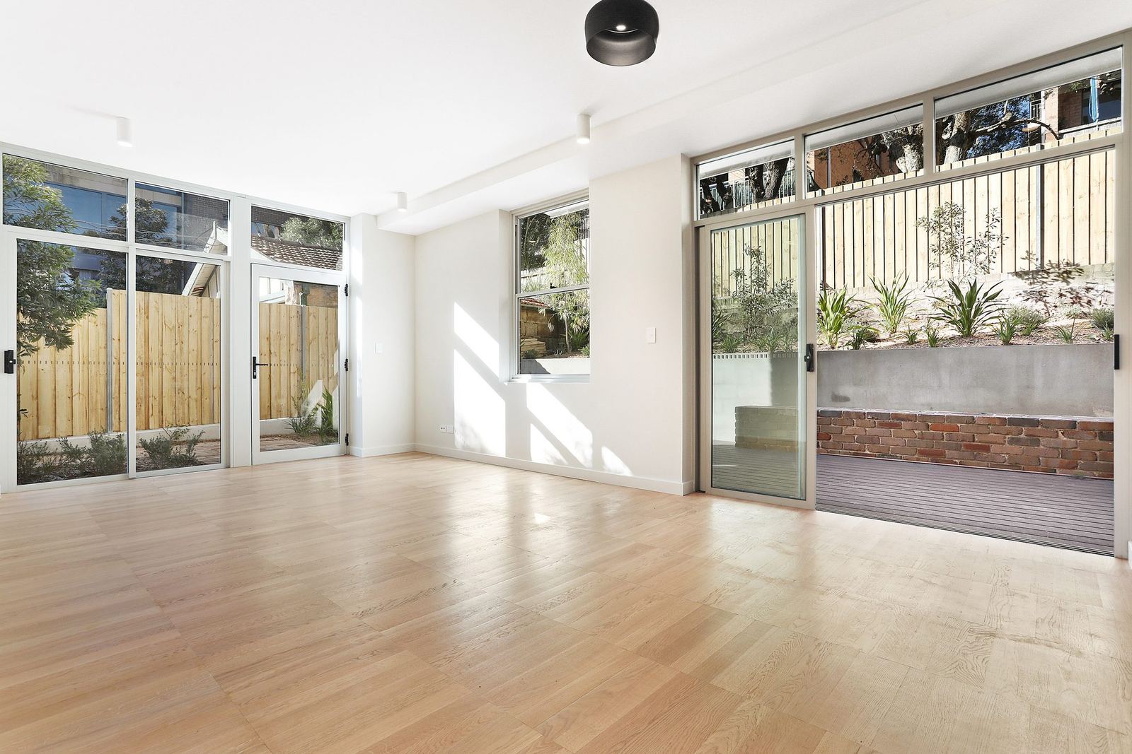 Queens Park Apartments, living room opening through glass doors to paved courtyard, built by HP Constructions with Ignite Architects