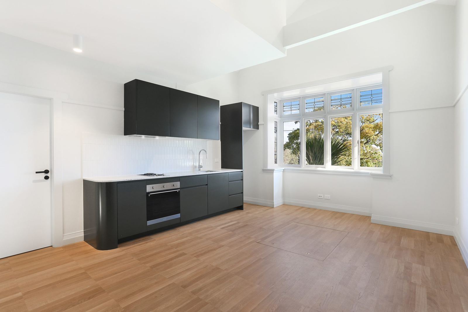 Queens Park Apartments, black kitchen with oven and windows to garden, built by HP Constructions with Ignite Architects