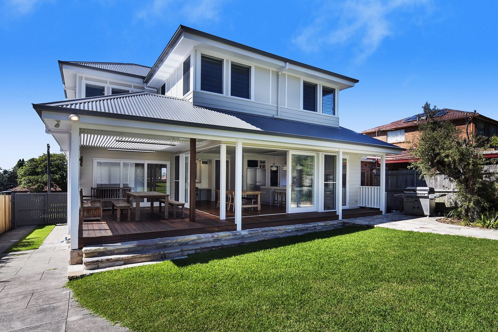 Seaforth, rear exterior with covered deck, lawn, sandstone paving and outdoor dining, built by HP Constructions with Playoust Churcher