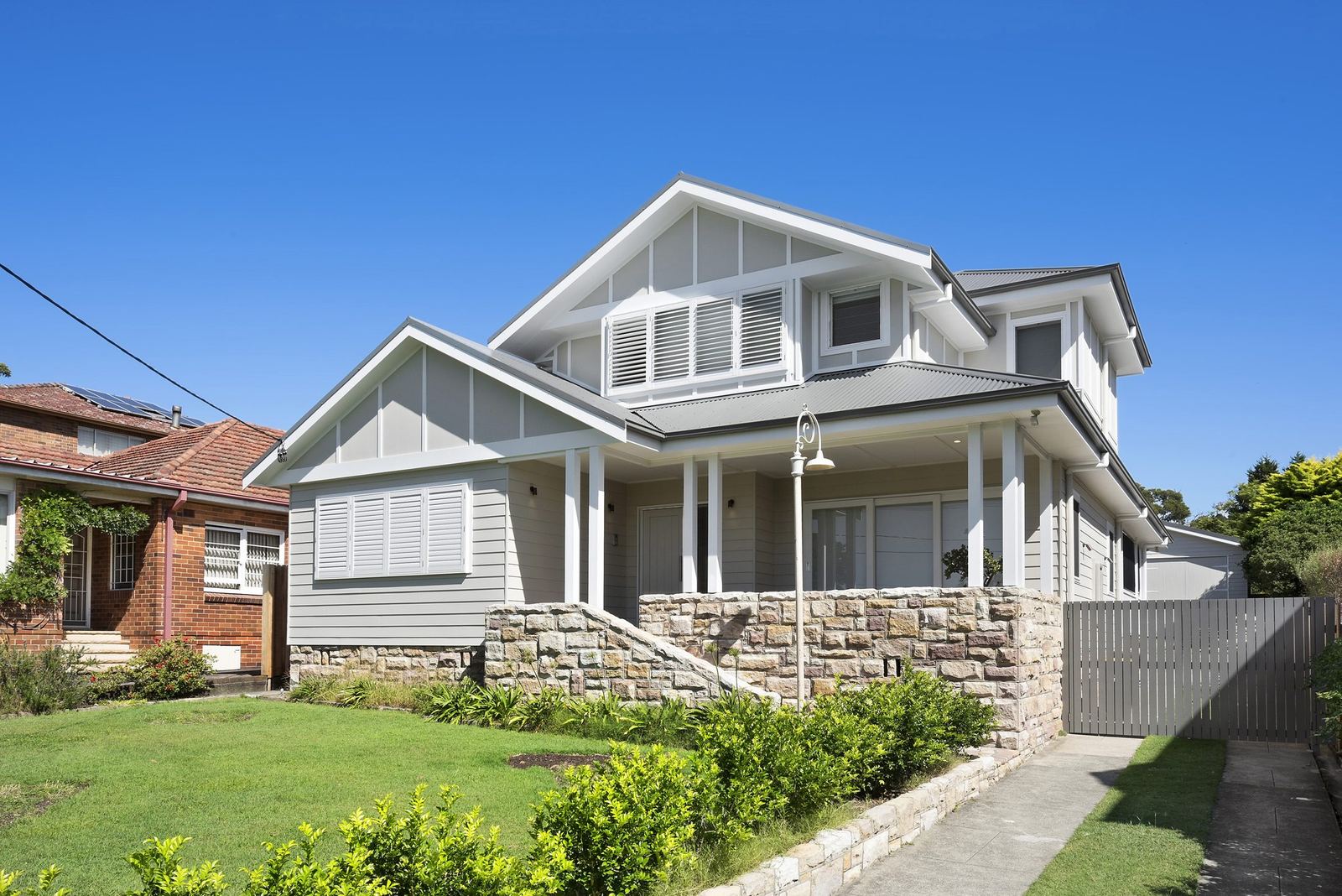Seaforth, street facade of a two-storey home with gable roof and sandstone base, built by HP Constructions with Playoust Churcher