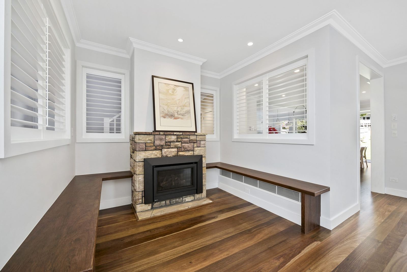 Seaforth, living room with stone fireplace, timber bench seat and plantation shutters, built by HP Constructions with Playoust Churcher