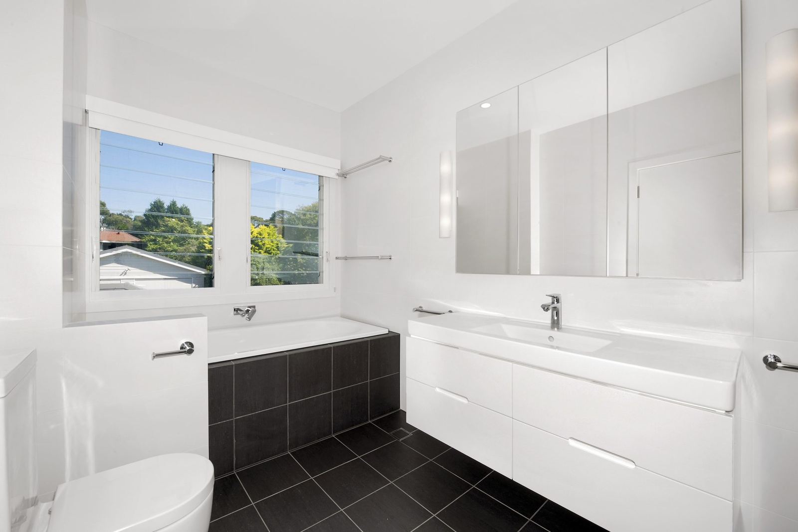 Seaforth, bathroom with white vanity, wall mirror, bath and dark-tiled floor, built by HP Constructions with Playoust Churcher