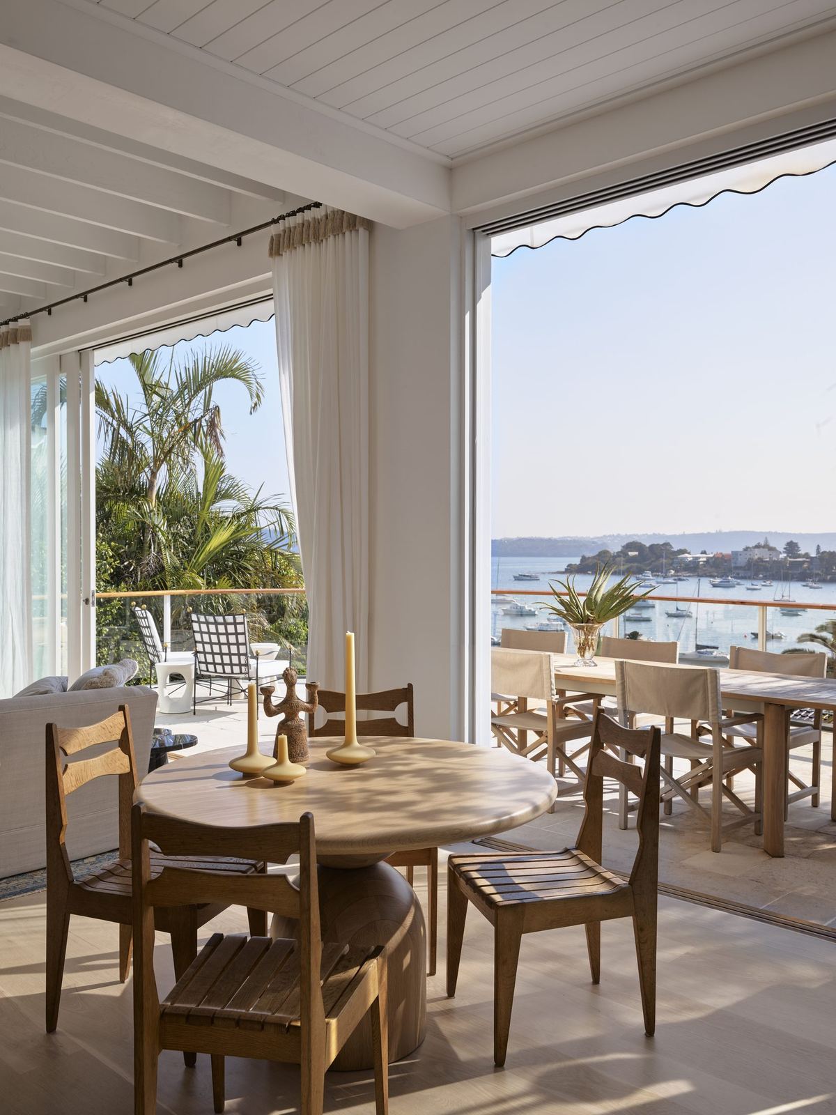 Vaucluse, dining area with round timber table opening to terrace and bay, built by HP Constructions with Alexander & Co