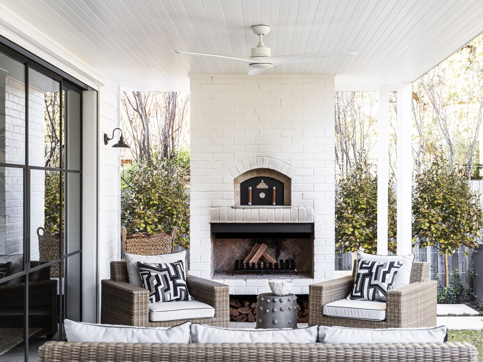 Willoughby, covered outdoor terrace with brick fireplace and wicker lounge, built by HP Constructions with Alexander & Co